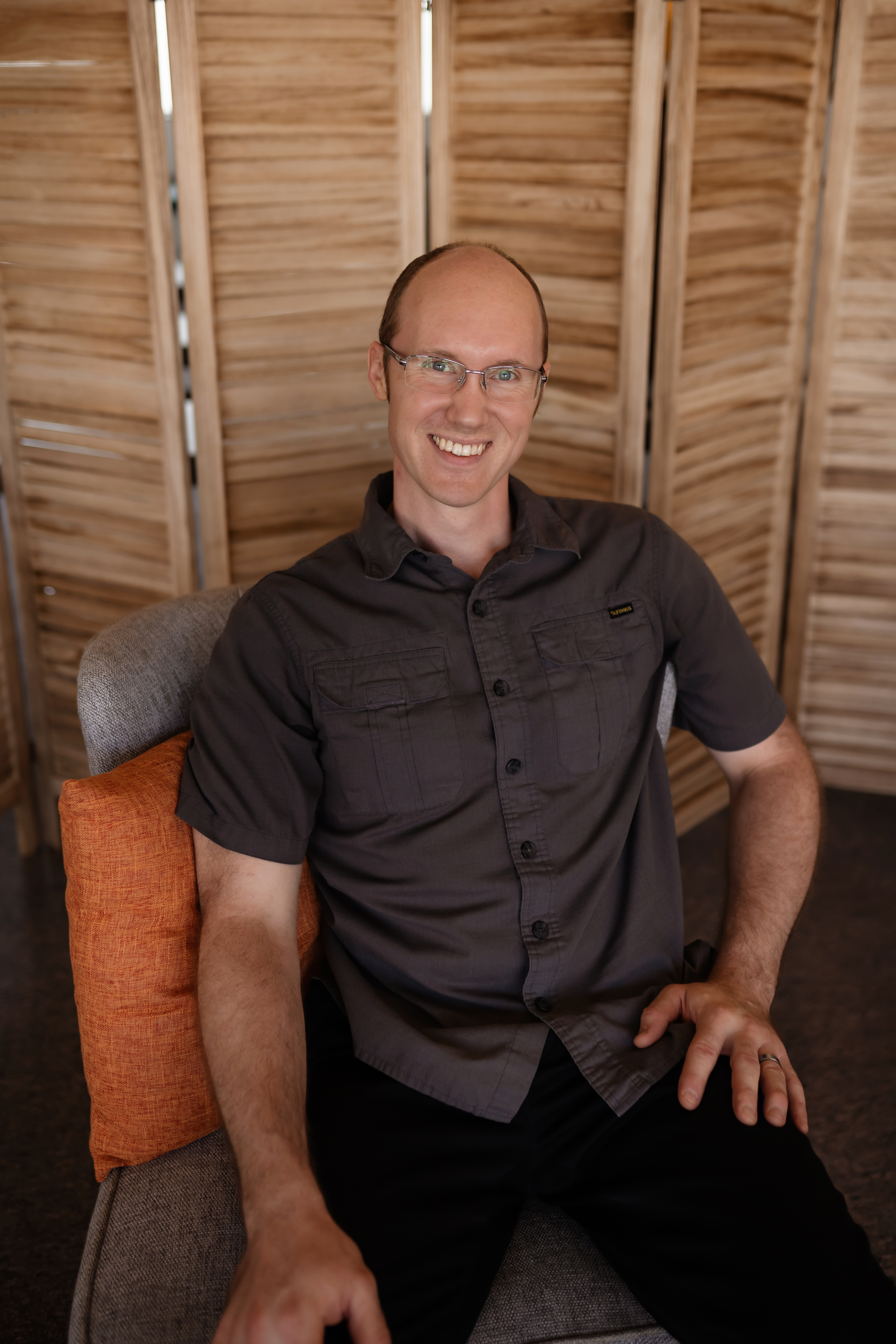 Jason Dixon smiling in a dark shirt, seated by a wooden folding screen